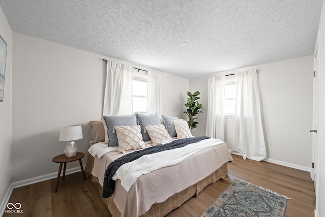 bedroom with wood finished floors, baseboards, and a textured ceiling