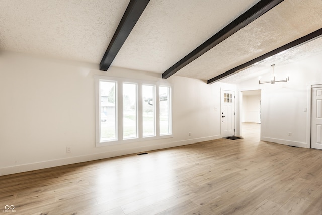 unfurnished living room featuring a textured ceiling, baseboards, lofted ceiling with beams, a chandelier, and light wood-style floors