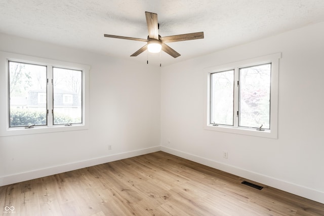 empty room with baseboards, ceiling fan, light wood-style flooring, and visible vents