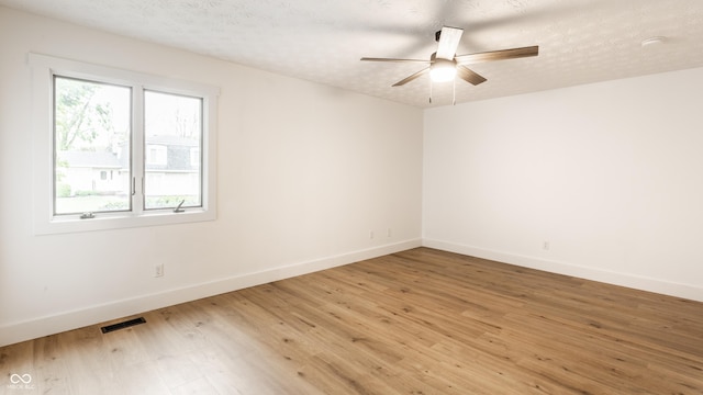 empty room featuring a ceiling fan, baseboards, visible vents, and light wood-type flooring