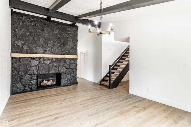 unfurnished living room featuring an inviting chandelier, stairs, baseboards, wood finished floors, and beamed ceiling