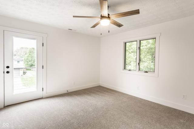 carpeted spare room featuring a textured ceiling, baseboards, visible vents, and ceiling fan
