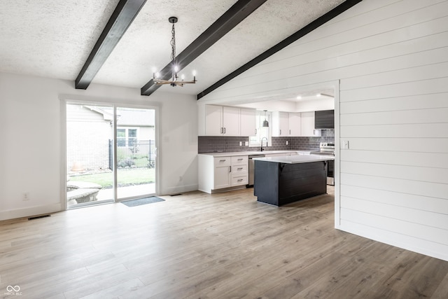 kitchen featuring decorative backsplash, light countertops, white cabinetry, a notable chandelier, and stainless steel appliances