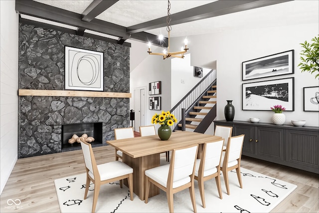 660 Sun Valley Ct, Indianapolis, IN 46217 - dining space with beam ceiling, light wood-style flooring, stairs, a chandelier, and a stone fireplace