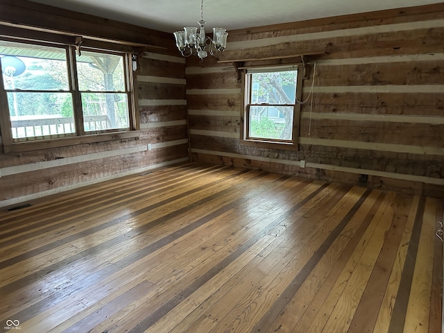 10770 W 650 S, Columbus, IN 47201 - spare room with wooden walls, visible vents, a chandelier, and hardwood / wood-style flooring