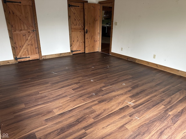 10770 W 650 S, Columbus, IN 47201 - unfurnished room with baseboards, a barn door, and wood finished floors