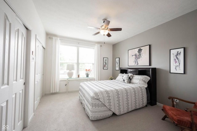 bedroom with light colored carpet, baseboards, and a ceiling fan