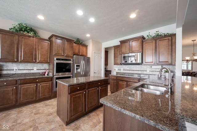 kitchen featuring appliances with stainless steel finishes, a sink, tasteful backsplash, dark stone countertops, and recessed lighting