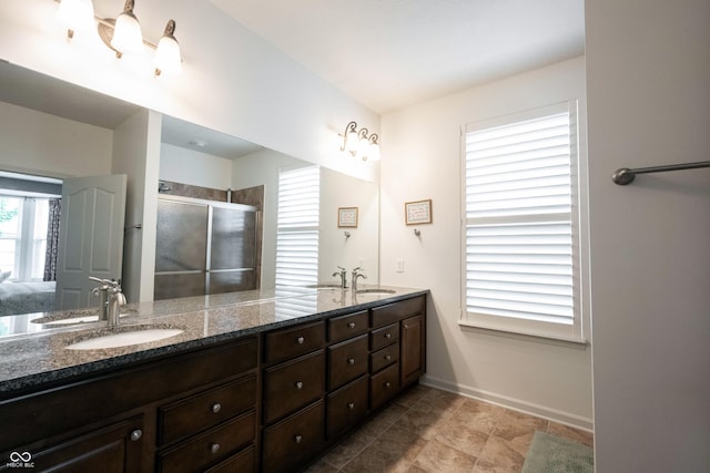 full bathroom with a stall shower, double vanity, baseboards, and ensuite bathroom