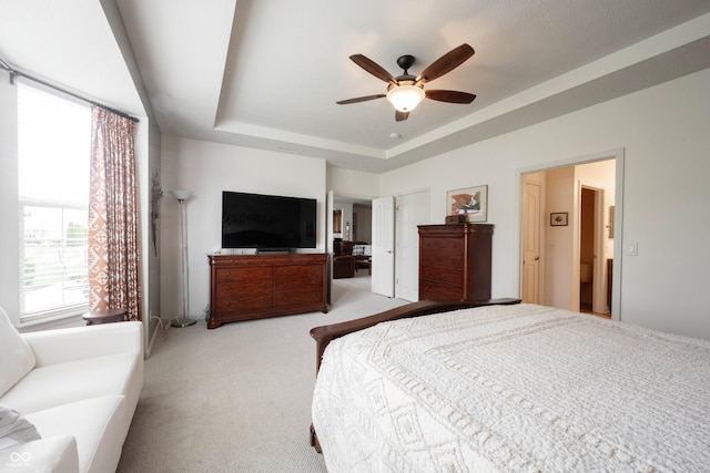 bedroom with carpet floors, a tray ceiling, and a ceiling fan