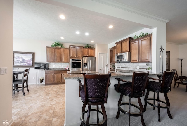 kitchen featuring stainless steel appliances, decorative backsplash, a breakfast bar area, brown cabinetry, and recessed lighting