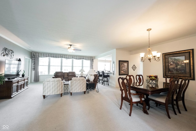 dining space with ornamental molding, a chandelier, light colored carpet, plenty of natural light, and ceiling fan