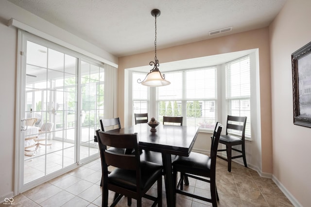 dining area with light tile patterned flooring, baseboards, and a textured ceiling