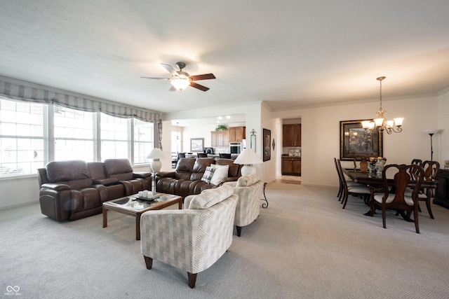 living area with light colored carpet, a chandelier, a ceiling fan, and crown molding