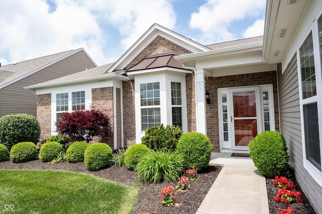 doorway to property with brick siding and a shingled roof
