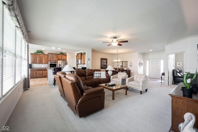 living area featuring light carpet, healthy amount of natural light, ceiling fan, crown molding, and a chandelier