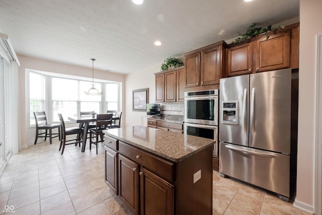 kitchen with stainless steel appliances, recessed lighting, stone countertops, a center island, and decorative light fixtures