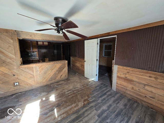 interior space with ceiling fan, wooden walls, and dark wood-type flooring