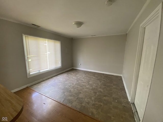 spare room with visible vents, crown molding, and baseboards