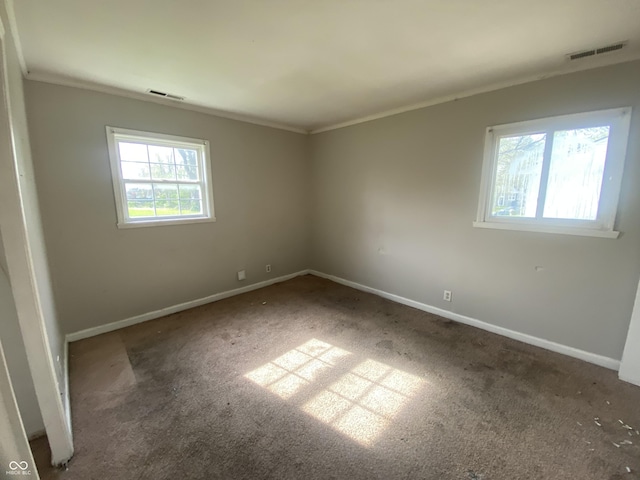carpeted spare room with visible vents, ornamental molding, and baseboards
