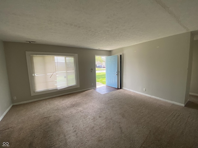 unfurnished room featuring a textured ceiling, carpet, and baseboards