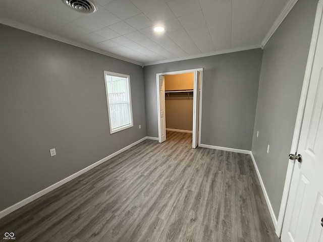 unfurnished bedroom featuring ornamental molding, visible vents, wood finished floors, and baseboards