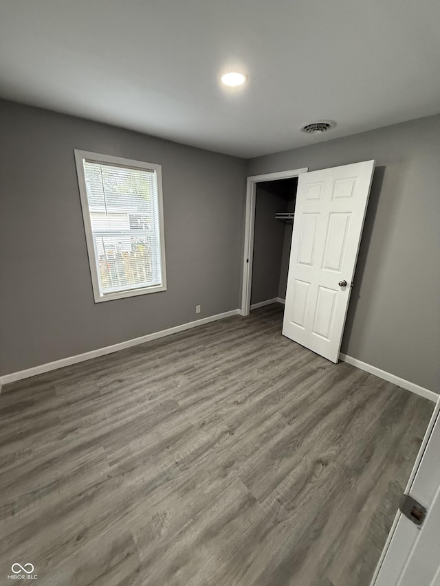 unfurnished bedroom featuring baseboards, visible vents, wood finished floors, and a closet