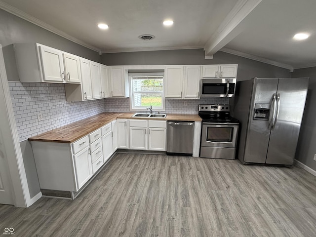 kitchen featuring appliances with stainless steel finishes, wooden counters, ornamental molding, light wood finished floors, and a sink