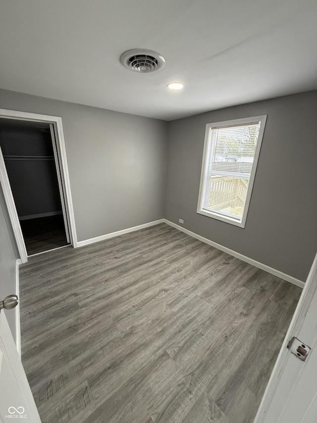 unfurnished bedroom with visible vents, wood finished floors, and baseboards
