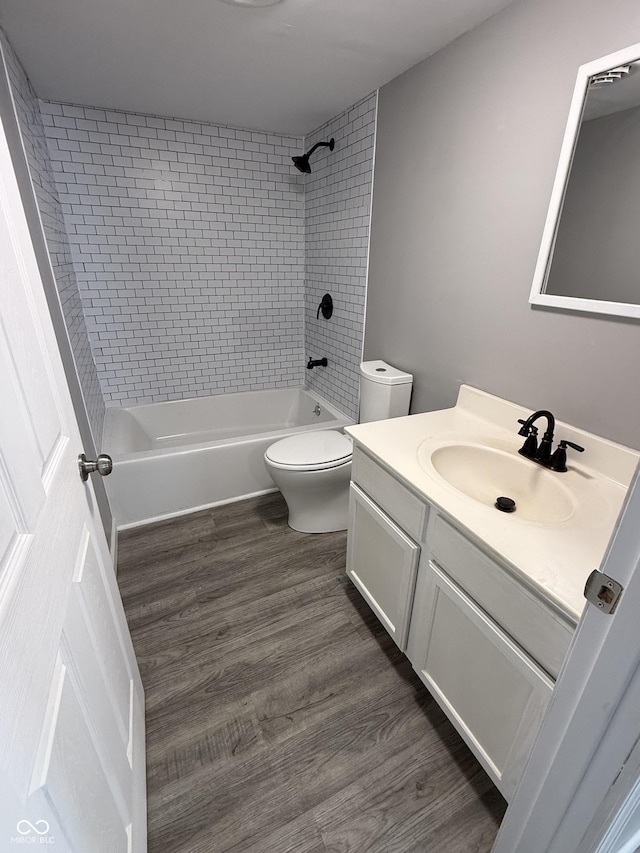 full bathroom featuring washtub / shower combination, toilet, wood finished floors, and vanity
