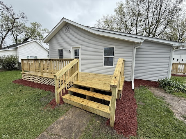 rear view of property featuring a lawn and a wooden deck