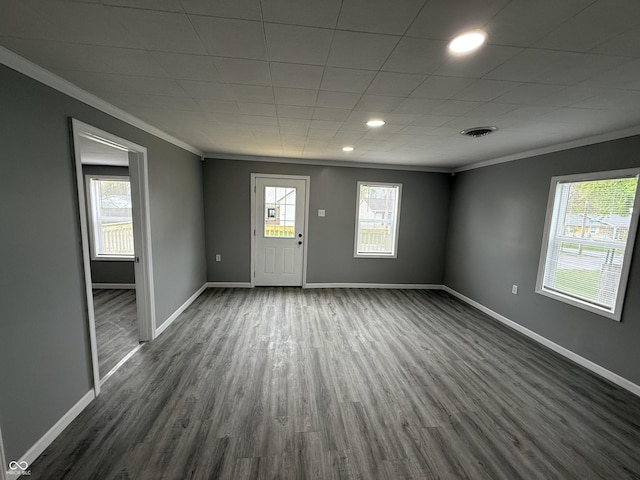 unfurnished room with dark wood finished floors, baseboards, ornamental molding, and visible vents