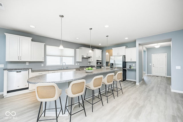 5110 Lilium Dr, Plainfield, IN 46168 - kitchen with stainless steel appliances, light wood finished floors, a spacious island, a breakfast bar, and recessed lighting