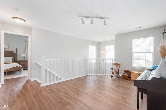 sitting room featuring a notable chandelier, visible vents, a healthy amount of sunlight, and wood finished floors