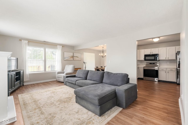 living room with light wood-style floors, baseboards, and a chandelier