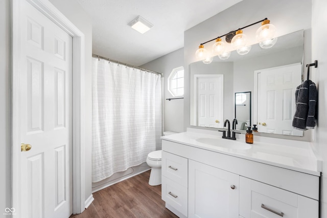 full bath featuring a shower with curtain, wood finished floors, vanity, toilet, and a tub to relax in