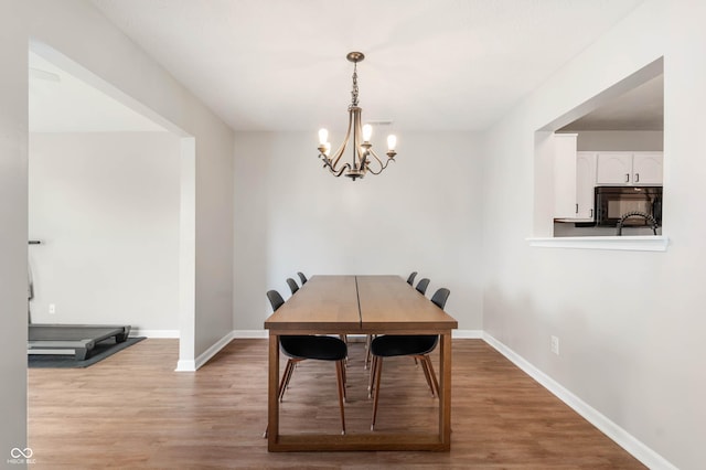 dining room with baseboards, wood finished floors, and a chandelier