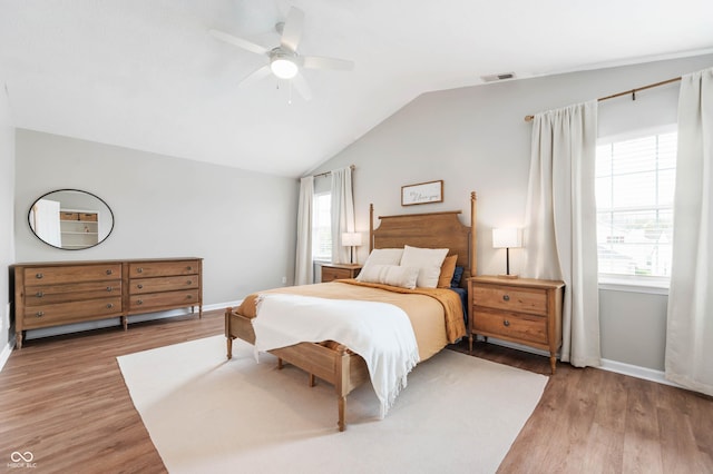bedroom featuring ceiling fan, baseboards, lofted ceiling, light wood-type flooring, and visible vents