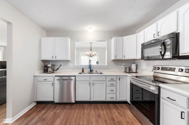 kitchen featuring light wood-type flooring, a sink, white cabinets, an inviting chandelier, and stainless steel appliances