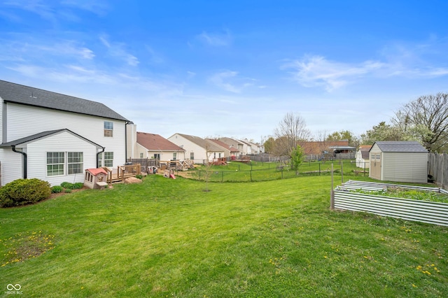 view of yard with a vegetable garden, a residential view, a fenced backyard, and a storage unit