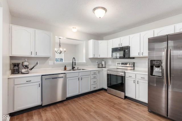 kitchen featuring a sink, white cabinetry, a chandelier, and stainless steel appliances