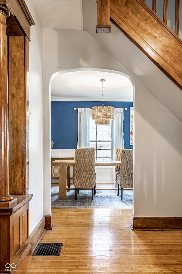 interior space featuring visible vents, arched walkways, light wood finished floors, and baseboards