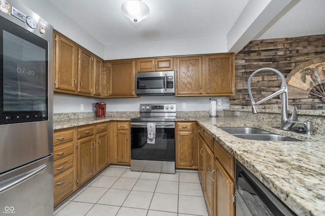 8140 Shorewalk Dr Unit C, Indianapolis, IN 46236 - kitchen with brown cabinets, light stone countertops, appliances with stainless steel finishes, a sink, and light tile patterned floors