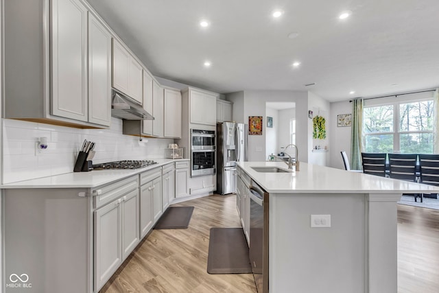 15120 Downham Dr, Fishers, IN 46037 - kitchen featuring under cabinet range hood, a sink, backsplash, light countertops, and appliances with stainless steel finishes
