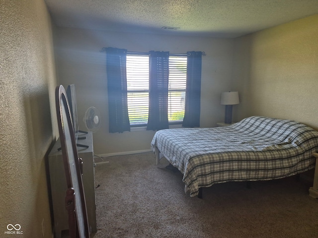 carpeted bedroom featuring a textured ceiling, a textured wall, visible vents, and baseboards