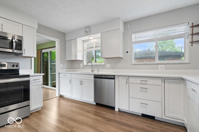 5719 Laurel Hall Dr, Indianapolis, IN 46226 - kitchen with appliances with stainless steel finishes, a sink, plenty of natural light, white cabinetry, and a textured ceiling