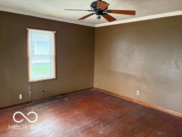 empty room with hardwood / wood-style floors, ornamental molding, a ceiling fan, and baseboards