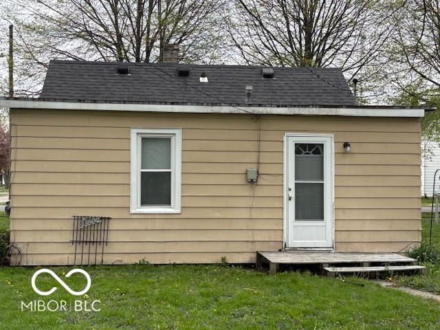 back of property featuring a yard and a shingled roof