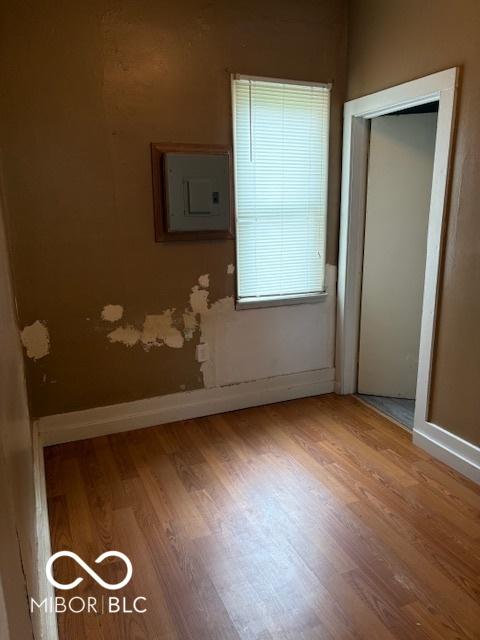 unfurnished bedroom featuring wood finished floors, electric panel, and baseboards