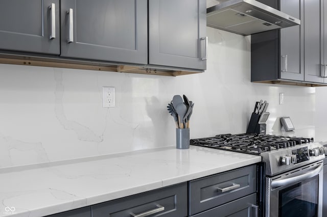 2226 Central Ave, Indianapolis, IN 46205 - kitchen featuring gray cabinetry, stainless steel range with gas stovetop, light stone counters, and wall chimney range hood